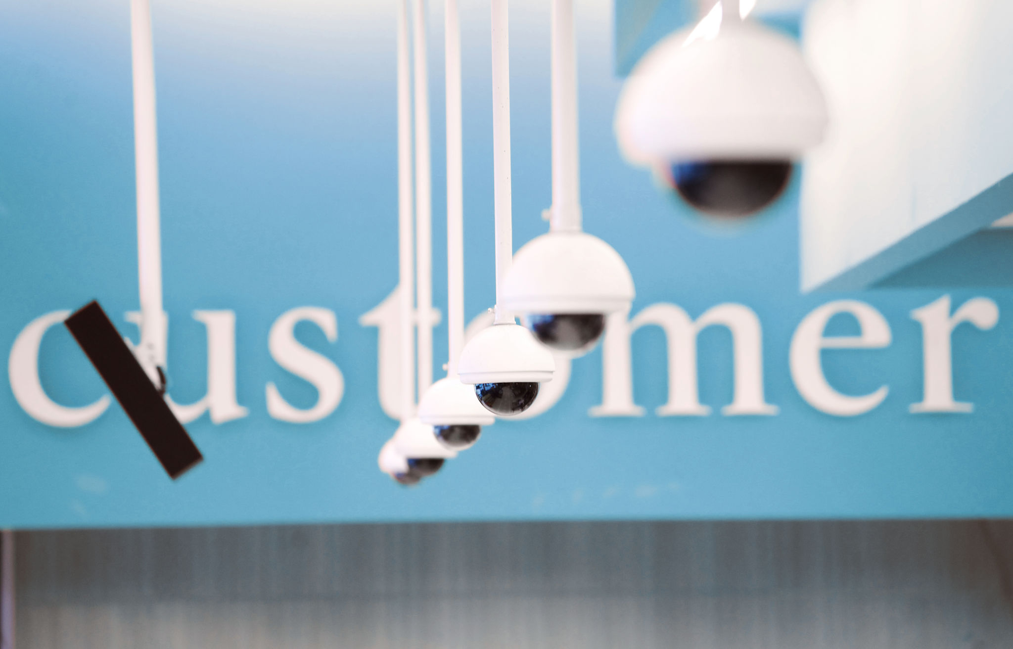 A row of ceiling mounted security CCTV cameras in a retail store. The cameras are used to monitor the floor for loos prevention and customer safety.
